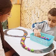 This image captures the intense focus during an ABA session. The task of arranging small objects requires precision and patience, helping to develop crucial pre writing skills and motor control.
