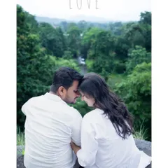 An intimate and romantic maternity portrait of a couple dressed in white, sitting together overlooking a lush green valley. This quiet moment, with their foreheads touching, beautifully captures the love and serenity of their journey together.