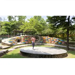 An outdoor amphitheater becomes a hub of activity and expression. The tiered seating, made from colorful recycled tires and natural stone, provides a playful and durable space for performances, gatherings, and imaginative play.