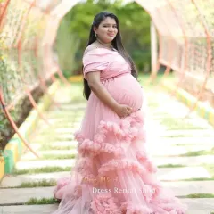 For a soft and romantic feel, this off-the-shoulder pink gown with layers of delicate ruffles is an ideal choice. It drapes beautifully to create a dreamy, ethereal look in any outdoor garden or park setting.