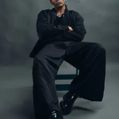 A full-length shot that showcases a modern, relaxed silhouette. The wide-leg pants and chunky boots create a contemporary look, and the low angle adds to the model's commanding presence.