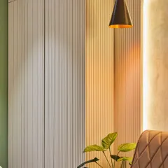 A close-up of the material details within the salon. The vertical fluted panels on the cabinetry add texture and a sense of height, while the warm, focused light from the pendant lamp creates an inviting and intimate mood.