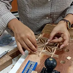 Anju carefully places the final infill pieces into her Asa-no-ha Kumiko pattern. This is a moment of pure concentration, where the entire intricate design comes together.