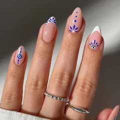 A close-up look at our detailed, hand-painted nail art. This set features delicate evil eye and geometric patterns on a natural base, combined with a modern French tip, showcasing our precision and creativity for custom designs.