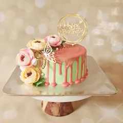 A simple cake can be elevated with perfect chocolate drips and beautiful flowers. This pastel green cake with a pink drip and a cluster of sugar flowers is both elegant and eye-catching.