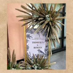 A chic welcome board for a Mehendi ceremony with a bohemian flair. The sign is adorned with an explosion of pampas grass, adding a touch of natural, free-spirited style to the entrance.