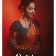 A classic bridal portrait of a Marathi bride, bathed in warm, dramatic red light that highlights her traditional saree and jewelry.