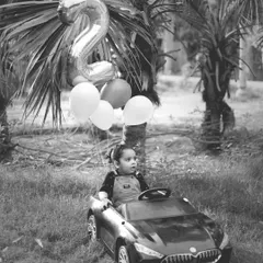 A classic black and white shot of a toddler in a toy car, part of our outdoor car-themed birthday shoot.