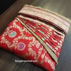 A classic red bridal Banarasi saree, pre-pleated and box-folded for a bride. I take special care with heavy bridal sarees to ensure the pleats are secure and the rich fabric is handled correctly, so the bride feels confident on her big day.