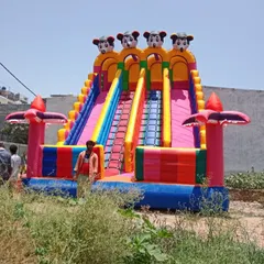This is my giant Mickey Mouse themed inflatable slide, standing tall at 18x26 feet. The person standing next to it shows just how big and impressive it is, making it a guaranteed centerpiece for any large event or mela.