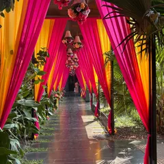 We created a grand and colorful entrance for this Mehendi ceremony. The long walkway was lined with lush greenery and covered with bright pink and yellow drapes, with hanging chandeliers adding a touch of elegance.