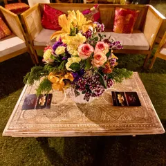 Even the guest seating is thoughtfully designed. Here, an intricately carved table and colorful floral centerpiece add to the festive decor of a Mehendi function.