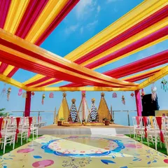A vibrant Haldi ceremony set against a stunning seaside backdrop. We used bright yellow and pink fabric drapes to create a festive canopy, with a custom-printed floor and floral arrangements that make for incredible photos and an even better experience.