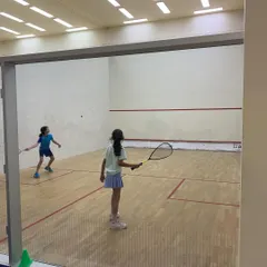 Two young female athletes compete in a spirited match during the Willingdon Squash Academy tournament.