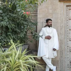 This client chose a regal white sherwani featuring intricate embroidery and dramatic draped sleeves. It's a powerful statement piece designed for a groom who wants a touch of royal flair.