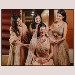 The bride Shreya shares a happy moment with her bridesmaids as they help her with her veil. The genuine smiles and supportive gestures capture the essence of friendship on a wedding day.