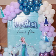 A closer look at the Frozen backdrop, showing the character cutouts and the shimmering metallic blue balloons.