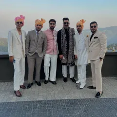 The groom's squad at a destination wedding, all dressed in our custom designs. The group showcases a mix of styles, including double-breasted suits, classic sherwanis, and a Jodhpuri jacket, all coordinated in a neutral color palette.