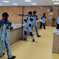 A line of our youth shooters in full competition gear during a practice session. An instructor observes to provide feedback on their standing rifle posture and technique.
