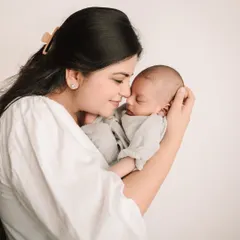 A mother's gentle touch as she holds her sleeping baby close, a timeless and emotional portrait.
