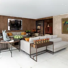 In this Camellias apartment, the living room is a study in layered textures and curated art. The custom ribbon veneer wall provides a warm, sculptural backdrop, while bespoke sofas and a Gopi Gajwani painting create a space that feels both sophisticated and deeply personal.
