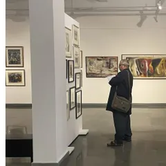 A visitor studies a collection of smaller works by Vidya Bhushan. My exhibitions often include a wide range of an artist's portfolio, from large canvases to intimate sketches.
