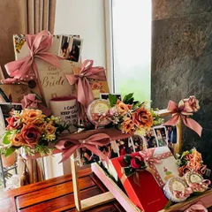 An angled view of the elaborate two-tiered wedding hamper. This perspective showcases the depth and layering of gifts, including personalized items on the top tier and curated products below, all unified by a soft pink color palette.