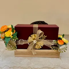 A single wedding gift elegantly wrapped and placed on a wooden platter, decorated with yellow-orange florals and golden accents.