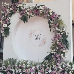 An elegant and classic engagement photo backdrop. We created this beautiful semi-circular arch with fresh lavender and white flowers, centered with the couple's custom wedding monogram.