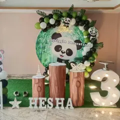 An adorable panda-themed 3rd birthday party. This setup features a custom backdrop with a large panda, bamboo-style pedestals, and a black, white, and green balloon arch.