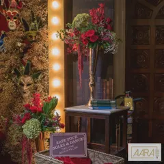 A cozy corner from our speakeasy-themed event, featuring a tall floral arrangement in reds and greens, vintage books, and a playful sign inviting guests to "Save your soles & dance!". These small details help build the narrative of the theme.