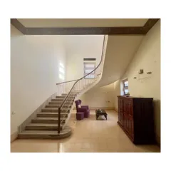 The elegant, curving staircase in the Art Deco building's main hall. This magnificent feature will be the centerpiece of the restored interior, a testament to the original craftsmanship.