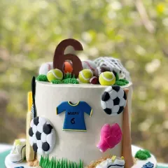 The perfect cake for a little sports champion. This design is covered in fondant decorations representing various sports, including soccer, tennis, and baseball, complete with a personalized jersey for the birthday boy.