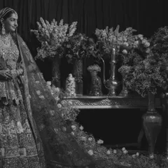 The bride in monochrome, her intricate lehenga and the floral decor taking on a timeless, ethereal quality. This artistic shot highlights the beauty of tradition in a classic format.