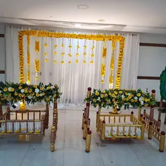 A simple and elegant floral decor for a twin baby girls' naming ceremony. We used two beautiful wooden cradles, a backdrop of white curtains with marigold garlands, and a peacock feather prop for a traditional touch.