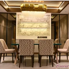 This dining area is designed for luxury, with a statement chandelier, a marble-finish accent wall, and custom-upholstered chairs. The lighting is designed to create a warm and inviting atmosphere for meals.