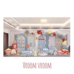 A full-stage view of our 'Vroom Vroom' transportation party. The setup includes a fire truck, bus, and car props, along with a road-themed backdrop and a colorful balloon arch.