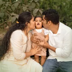 A "kiss sandwich" for the birthday girl! This candid outdoor family portrait is overflowing with love and affection, a perfect memory from her first birthday shoot.
