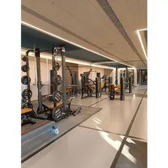 The fully-equipped gym at 'The Bandra Project'. The design uses a grey vinyl floor with black line details, while the ceiling coves are painted blue to add a dynamic element to the workout space.