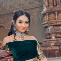 A smiling model wearing a silver-finish diamond choker with a green stone drop. This elegant piece is perfect for a reception or engagement party.