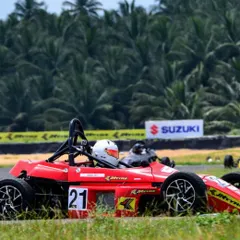 The number 21 Formula LGB car at speed, framed by the lush greenery of the Kari Motor Speedway.