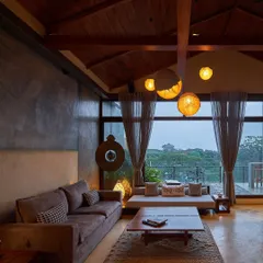 The upper living area features a sloping roof made of natural timber and walls finished with pigmented cement. A vintage astro-globe and large windows overlooking the greenery bring in a sense of nostalgia and calm.