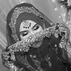 A timeless black and white portrait of a Muslim bride, her face partially veiled, highlighting the delicate embroidery of her hijab and her expressive eyes.