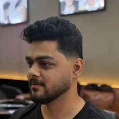 The final result of a clean fade and beard lineup. The hair on top is styled with volume and texture, while the sides are faded down to the skin for a super clean finish.