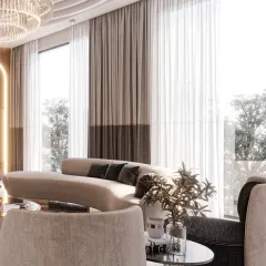 A view across the drawing room, showing how the floor-to-ceiling windows flood the space with natural light. The curved sofa and layered curtains soften the room's grand scale.