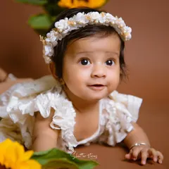 A beautiful close-up of a baby girl during her sitter session, surrounded by sunflowers and wearing a delicate floral headband.