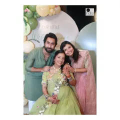 A happy family portrait with the parents-to-be and a sibling, all smiles in front of the beautiful event decor.
