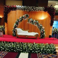 This is a classic wedding reception stage I designed at the Eros Hotel. The setup features a grand floral arch in red and white, a smaller broken arch for a modern touch, and a clean white diwan, creating a rich and elegant look.