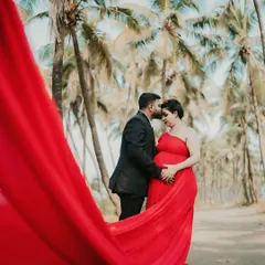 An intimate moment during a maternity shoot. The flowing red trail of the gown wraps around the couple, symbolizing the love that surrounds their growing family.