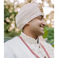 A candid, smiling profile of the groom in his wedding attire, capturing a moment of pure happiness.